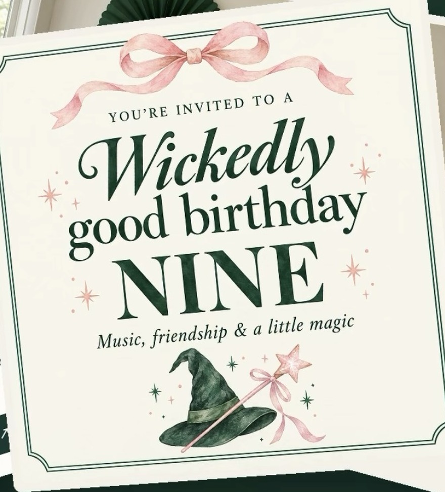 A cream, emerald and pink birthday invitation with a watercolour witch hat, a wand and a pink bow.